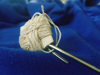 Close-up of knitting needles and wool on blue textile