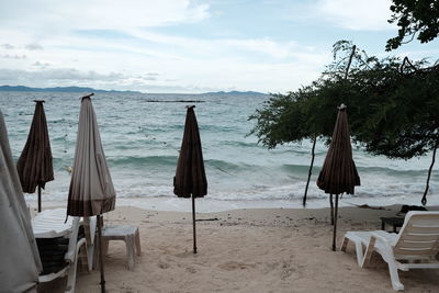 Deck chairs on beach against sky