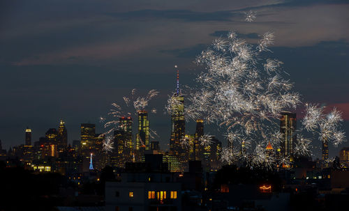 Firework display and illuminated buildings in city at night