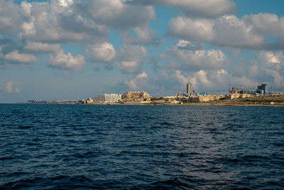 Scenic view of sea by buildings against sky