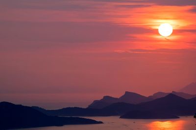 Scenic view of silhouette mountains against orange sky