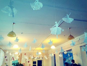 Low angle view of illuminated light bulbs hanging against sky