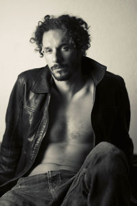 Portrait of young man sitting against wall