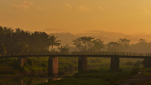 Bridge over river against sky during sunrise