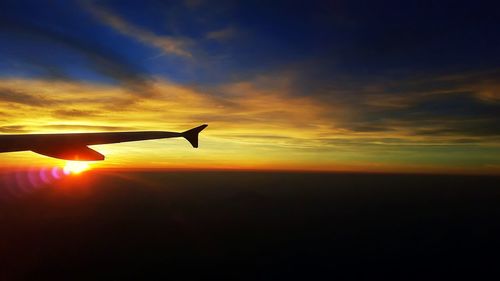 Silhouette hand holding orange sky during sunset