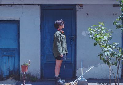 Woman standing against blue door