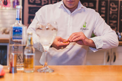 Midsection of bartender preparing drink at counter