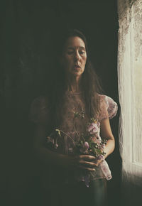 Woman with bouquet of flowers near a window