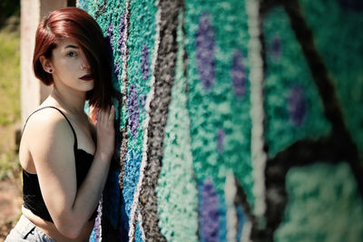 Portrait of young woman leaning against wall