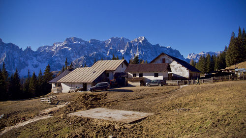 Houses on field by mountain against blue sky