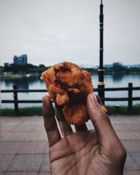 Close-up of hand holding ice cream against river