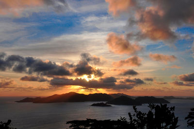 View of the sunset over the island of praslin with vibrant sky and the ocean with reflections