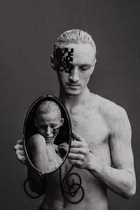 Man holds a mirror in his hands, in the reflection of which is a woman with tattoos with a qr code 