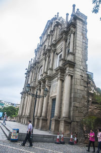 Low angle view of people walking against building