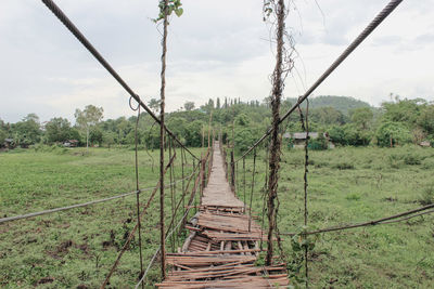 Broken rope bridge over grassy field