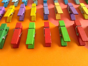 High angle view of colorful wooden clothespins arranged on colored background