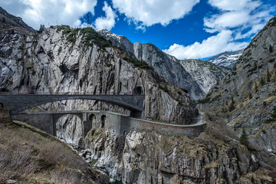 Bridge over river amidst mountains against sky