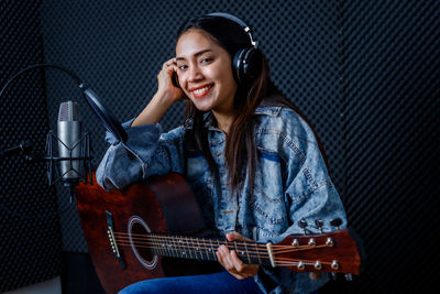 Smiling young woman playing guitar