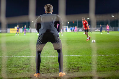 Rear view of woman playing soccer ball on grass