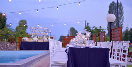 Chairs and table by swimming pool against sky