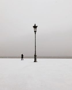 People on snow covered street against sky