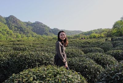 Portrait of smiling young woman standing on land against sky