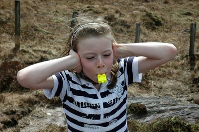 High angle view of girl blowing whistle standing on field