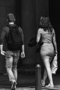 Rear view of man and woman walking on city street