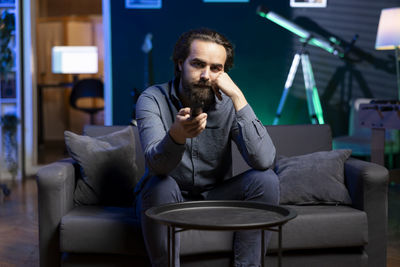 Young man using phone while sitting at home