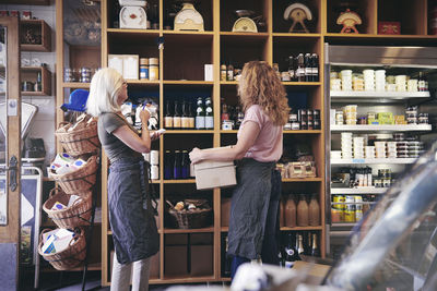 Female coworkers standing by rack in deli