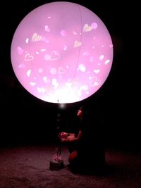 Low angle view of woman holding umbrella at night