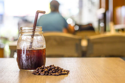 Close-up of drink and coffee beans on table