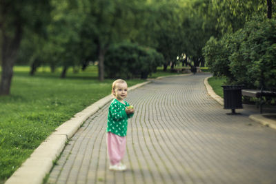 Full length of baby girl looking away while standing on footpath