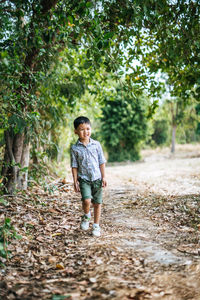 Full length portrait of boy standing in forest