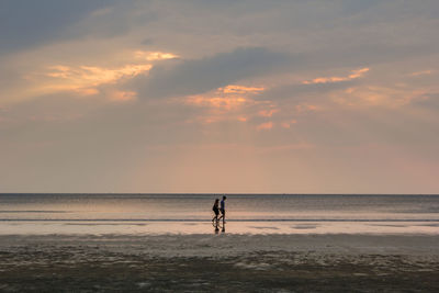 Man standing on beach against sky during sunset