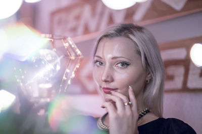 Portrait of beautiful woman holding illuminated light bulb