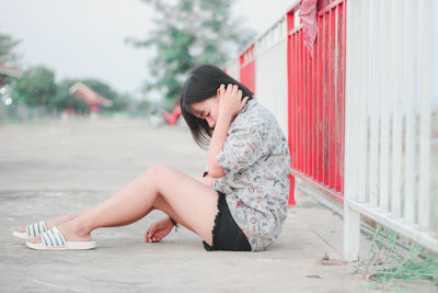 Side view of young woman sitting outdoors