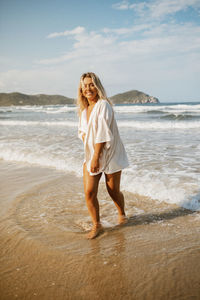 Portrait of young woman standing at beach