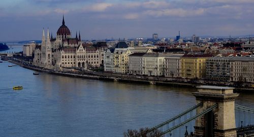 Chain bridge over danube river with hungarian parliament building in city