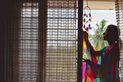 Side view of woman looking dreamcatcher at home