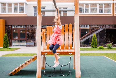 Full length of girl playing in park near building