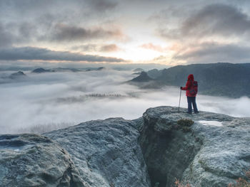 Alone woman hiker in rocks while extreme misty weather. autumn hike in rocks for hard adventurer