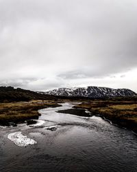 Scenic view of lake by snowcapped mountains against sky