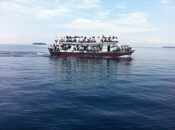 People on boat in sea against sky