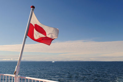 Red flag on sea against sky