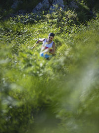 Athlete running between grass on mountain at forest