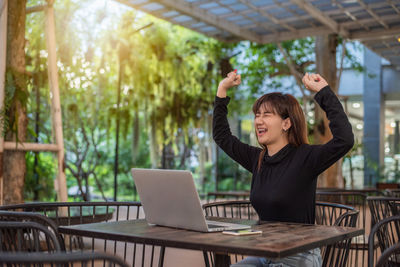 Young woman using phone while sitting on table