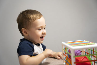 A happy toddler boy is playing a game with sensory colorful balls. 