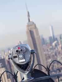 Close-up of coin-operated binoculars against buildings in city