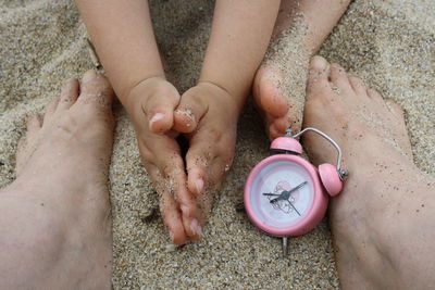 Low section of mother and baby sitting on sand at beach